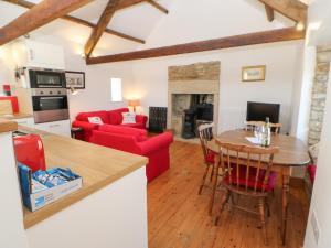 a kitchen and living room with a table and red chairs at Dove Cottage in Hexham