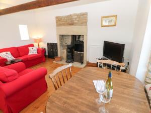 a living room with a table and a red couch at Dove Cottage in Hexham