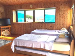 een slaapkamer met 2 bedden en een raam bij Minshuku Yadokari in Zamami
