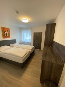 a bedroom with two beds and a wooden table at KM Hotel Murtal in Knittelfeld