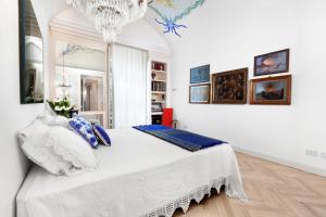 ein weißes Schlafzimmer mit einem großen Bett und einem Kronleuchter in der Unterkunft AMORE RENTALS - Casa Sofia in Sorrent