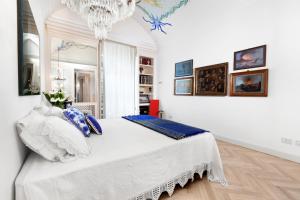 biała sypialnia z dużym łóżkiem i żyrandolem w obiekcie AMORE RENTALS - Villa Sofia w Sorrento