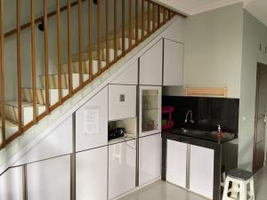 una cocina con armarios blancos y una escalera en Grand Sofia Family GH en Bandung
