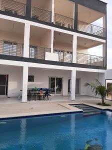 an apartment building with a swimming pool in front of it at Résidence Fleur de la petite côte in Mbour