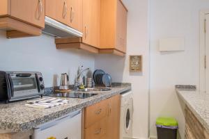 uma pequena cozinha com um lavatório e um micro-ondas em Riverside Triana Apartment em Sevilha
