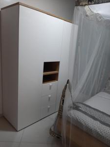 a white bedroom with a bed and a dresser at Résidence Fleur de la petite côte in Mbour