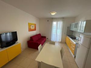 a living room with a red couch and a kitchen at Residence Al Mare - Agenzia Cocal in Caorle