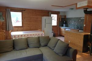 a living room with a couch and a kitchen at L'Echaillon - Ancolie in Névache