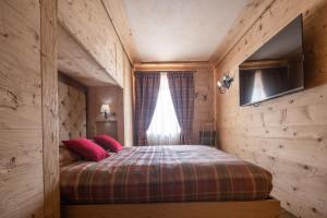 a bedroom with a bed with red pillows and a window at Cortina Deluxe Chalet R&R in Zuel