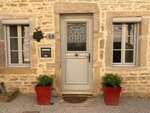 eine Tür eines Steingebäudes mit zwei Topfpflanzen in der Unterkunft Coeur de Pommard in Pommard