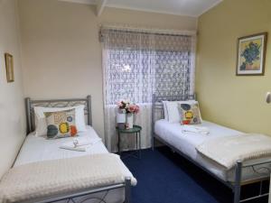 two twin beds in a room with a window at Beech Forest Cottage (Cozy Otways Accommodation) in Beech Forest