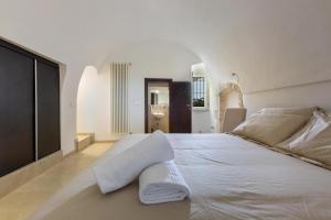 a white bed with two towels on top of it at Casa degli Amici by BarbarHouse in Ostuni