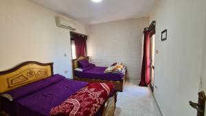 two beds in a small room with purple sheets at شاليه غرفتين بالمعمورة الشاطى على البحر صف ثان in Alexandria