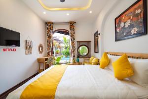 a bedroom with a large bed with yellow pillows at An Nhien Boutique Villa in Hoi An