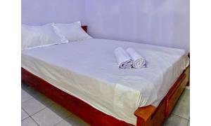 a bed with white sheets and towels on it at Griya Asri Syariah Mitra RedDoorz in Rogojampi