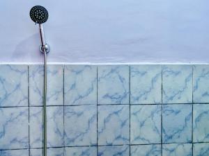 a shower with blue tiles on a wall at Griya Asri Syariah Mitra RedDoorz in Rogojampi +17 photos