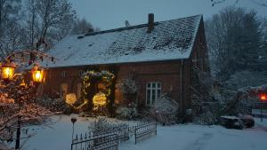 uma casa com uma coroa de Natal na neve em Oberstübchen im Alten Pfarrhof em Behren-Lübchin