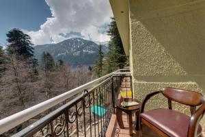 a balcony with a chair and a view of a mountain at Regenta Place Green Leaf Manali- A Centrally Heated Resort in Manāli