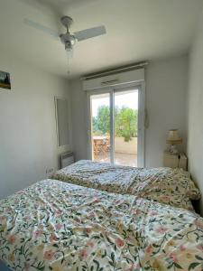 1 Schlafzimmer mit einem Bett mit Blumenbettdecke und einem Fenster in der Unterkunft Quiet apartment with terrace & pool - Cannes in Cannes