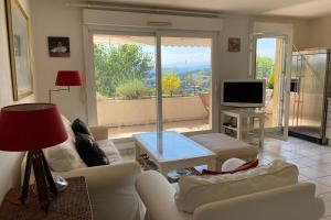 un soggiorno con divani bianchi e TV di Quiet apartment with terrace & pool - Cannes a Cannes