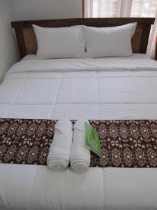 a bed with two rolls of white towels on it at Gedong Khayangan in Tabanan +6 photos
