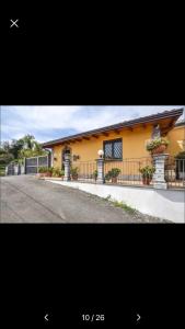 uma casa amarela com uma cerca e uma rua em Casa vacanza tra Etna e Taormina Villa Ginevra em Piedimonte Etneo