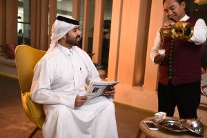 a man sitting in a chair and a man standing at Sealine Beach, a Murwab Resort in Mesaieed