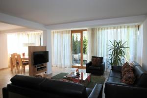 a living room with a black leather couch and a television at Landhaus Alpenflair Whg 403 in Oberstdorf