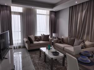 a living room with two couches and a tv at Al Safwa One in Al Ḩadd