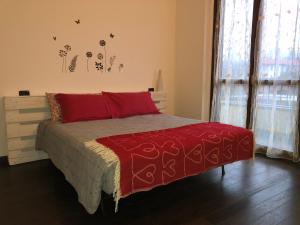 a bedroom with a bed with a red comforter at Benvenuti a casa EMAGAL a due passi dal fiume in Sesto Calende