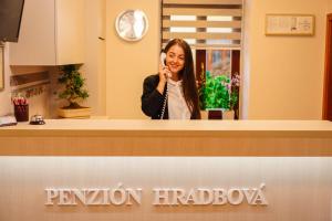a woman talking on a cell phone behind a counter at Penzión Hradbová Residence & Spa in Košice