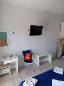 Habitación con silla y TV en la pared. en Kassandros Studios - Hanioti Halkidiki en Hanioti