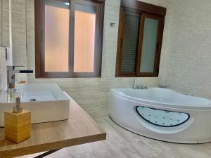 een badkamer met een groot bad en een wastafel bij La casita del Agua in Úbeda