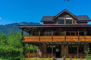 a large wooden house with a large deck at StayVista at The Kathguni House in Manali With Private Lawn in Manāli