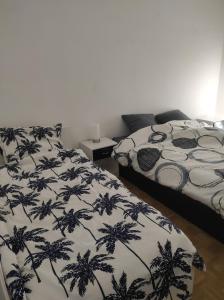 een slaapkamer met 2 bedden en een zwart-wit dekbed bij Appartement 70m² Pierrelatte Cosy, NETFLIX+WIFI in Pierrelatte