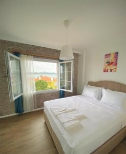 a bedroom with a large bed and a large window at Cunda Kordon Otel in Ayvalık