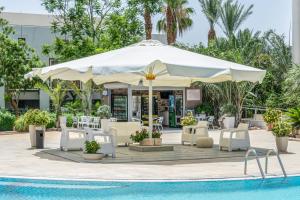 una piscina con sillas y una sombrilla junto a una piscina en Royal park-Garden Apartment, en Eilat