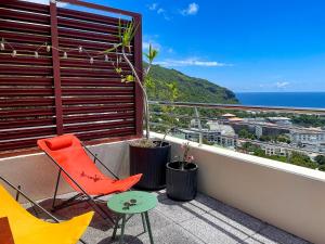 d'un balcon avec une chaise rouge et une table. dans l'établissement Le Pétrel dans les Nuages - Appartement avec terrasse en plein ciel dominant Saint-Denis, à Saint-Denis