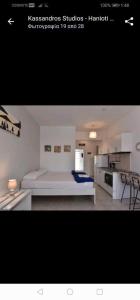 a white bedroom with a bed and a kitchen at Kassandros Studios - Hanioti Halkidiki in Hanioti