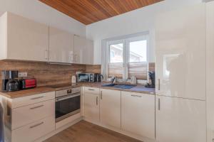 a kitchen with white cabinets and a window at Haus Relax, Whg 3 in Duhnen