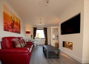 a living room with a red couch and a fireplace at Annie's Corner - Fort William in Caol