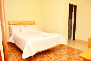 a bedroom with a bed with white sheets and pillows at Musanto Hotel in Gisenyi