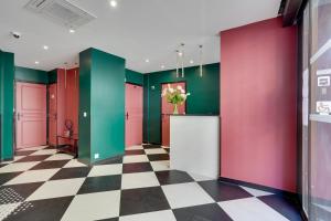 um corredor com paredes coloridas e um piso xadrez em Hotel B Square em Paris