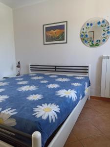 een bed met een blauwe deken met witte bloemen erop bij Portoselvaggio Villa Martina in Santa Caterina di Nardò