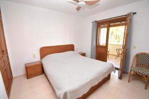 a bedroom with a bed and a chair and a window at Casa Rosa Javea in Jávea
