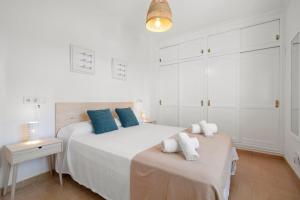 una camera bianca con un grande letto con cuscini blu di Punta Prima Apartments a Punta Prima