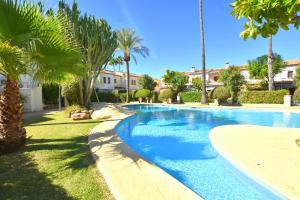 a swimming pool with palm trees and a building at Casa Rosa Javea in Jávea