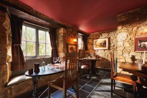a restaurant with tables and chairs in a room with stone walls at The Masons Arms in Branscombe