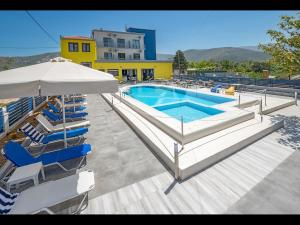 een zwembad met ligstoelen en een parasol bij Thassian Riviera Hotel in Skala Prinou
