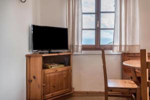 un televisor sentado en un soporte de madera junto a una ventana en Sallrain Hof Apartment 2, en Collalbo